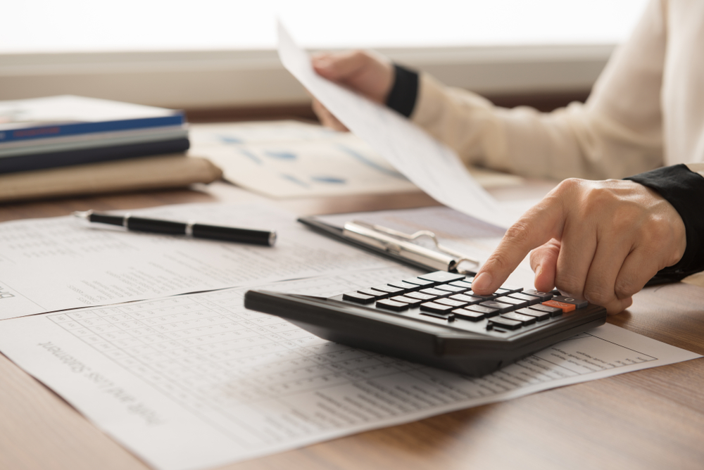 Hand entering figures on a calculator while holding a printed statement